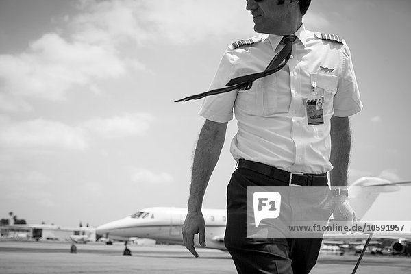 Black and white image of male private jet pilot arriving at airport
