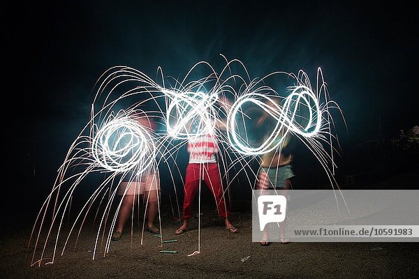 Four adult friends making sparkler patterns in darkness on Independence Day  USA