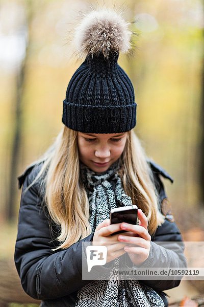 Mädchen mit Smartphone im Herbstwald