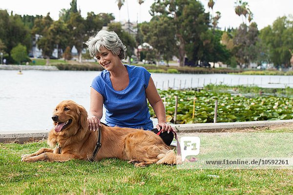 Reife Frau sitzend mit Hund im Park
