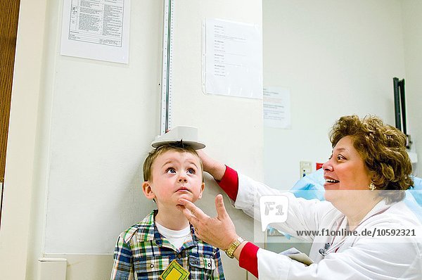 Female doctor checking height of young boy