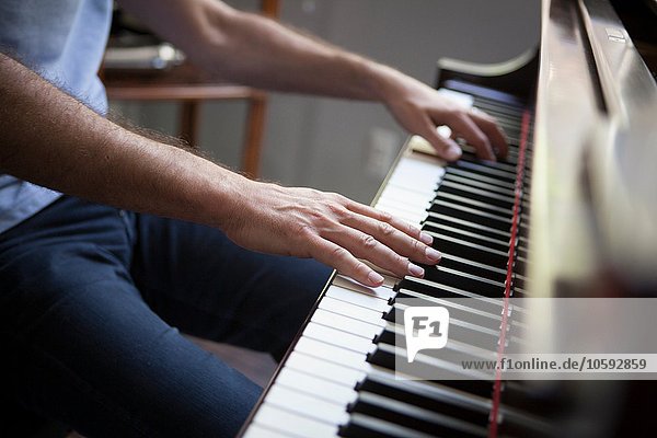 Cropped view of mature man sitting playing piano