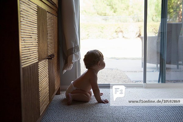 Side view of baby boy sitting in front of patio doors  looking away