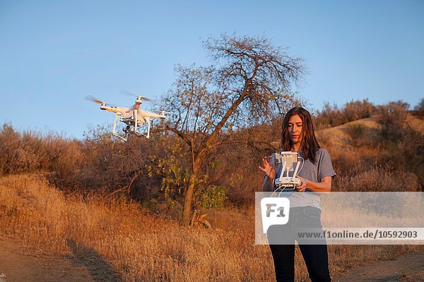 Female commercial operator on scrubland flying drone  looking down  Santa Clarita  California  USA