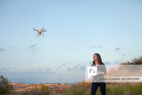 Female commercial operator flying drone looking up smiling  Santa Clarita  California  USA