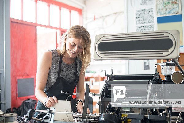 Junge Frau arbeitet mit traditioneller Buchdruckmaschine in der Werkstatt