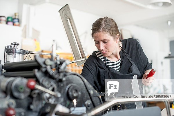 Female printer preparing print machine in workshop