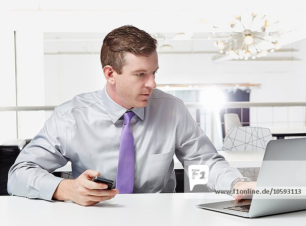 Mittlerer erwachsener Geschäftsmann am Schreibtisch sitzend  mit Laptop