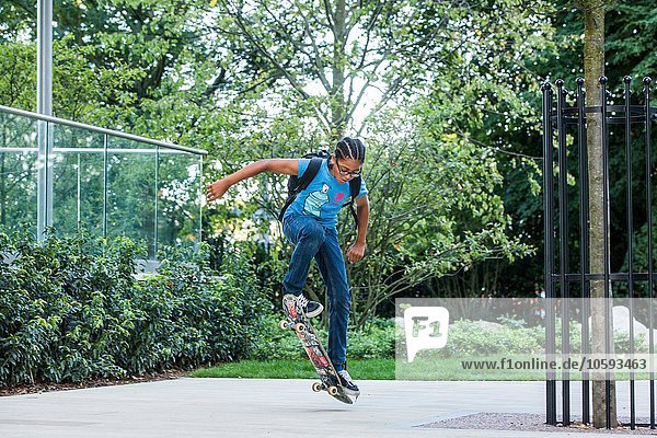 Junge macht Skateboard-Trick auf städtischem Bürgersteig