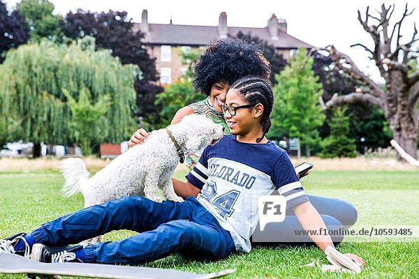 Boy and mother playing with dog in park