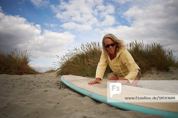 Seniorenfrau am Strand  Surfbrett gewachst