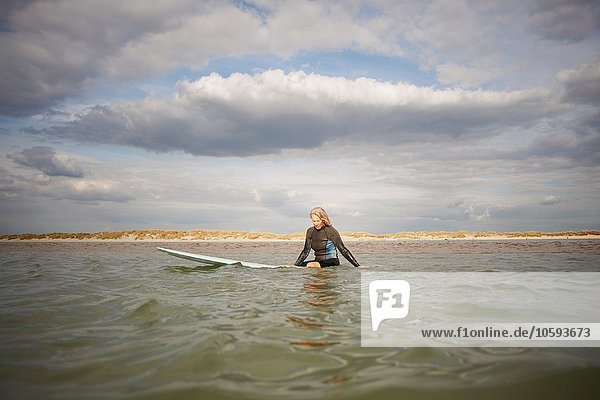 Seniorin auf dem Surfbrett im Meer sitzend