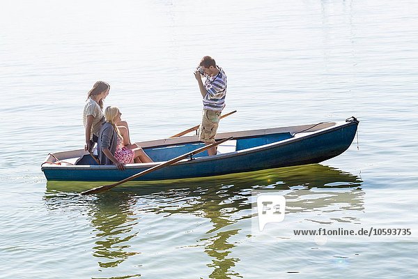 Seitenansicht eines jungen Mannes im Boot auf dem See  der Frauen fotografiert.