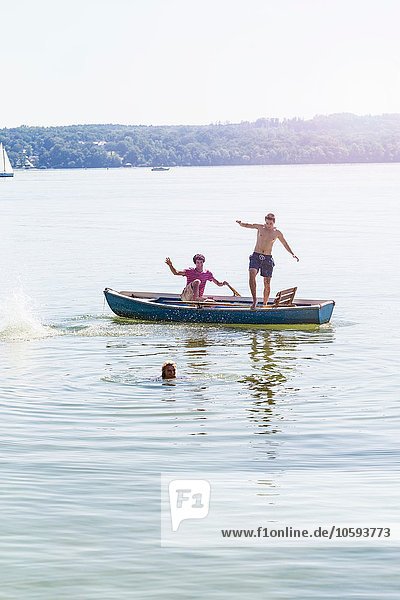 Freunde springen vom Boot und schwimmen im See  Schondorf  Ammersee  Bayern  Deutschland