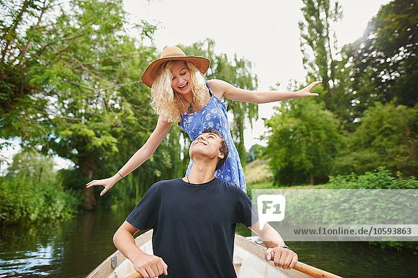 Junge Frau mit Freund im Ruderboot auf dem Fluss stehend
