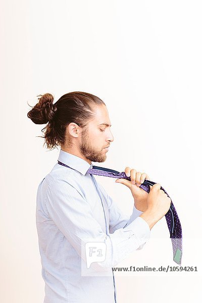Junger Mann mit Haaren in Brötchen  sich anziehen  Halsband binden