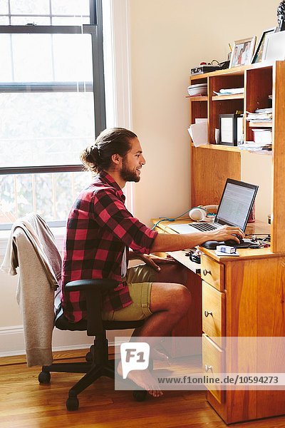 Young man sitting at desk  using laptop