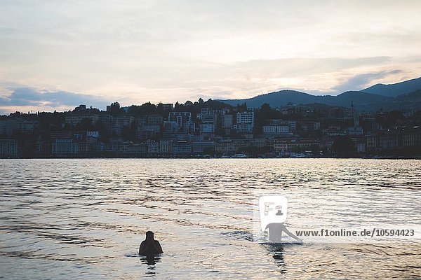 Zwei Scherenschnitt-Touristen schwimmen im Luganersee,  Schweiz