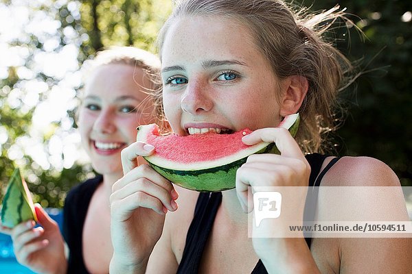 Zwei Teenagermädchen beim Essen von Wassermelonenscheiben im Garten