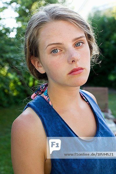 Portrait of sullen teenage girl in garden