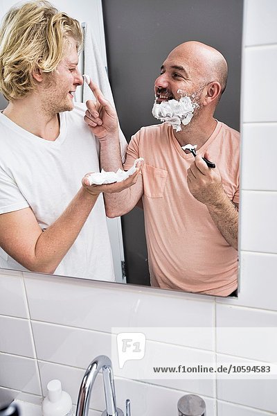 Bathroom mirror image of male couple fooling around whilst shaving