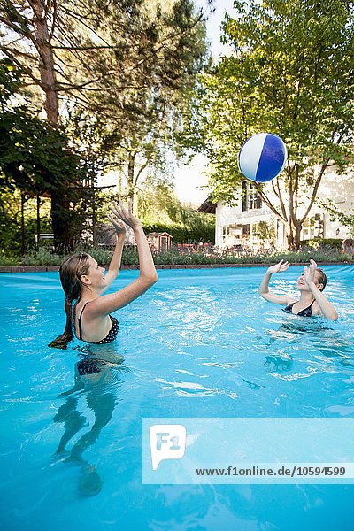 Zwei Teenager-Mädchen spielen mit Beachball im Schwimmbad