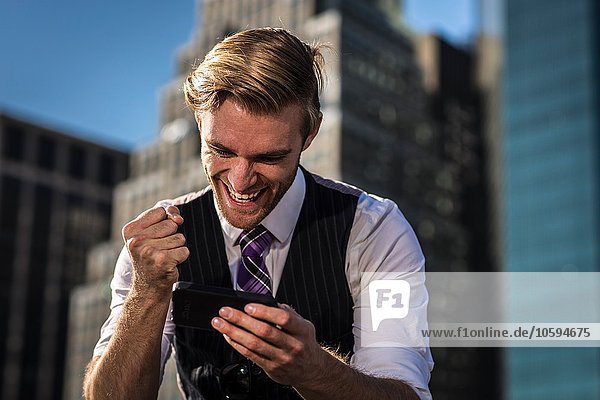 Junger Geschäftsmann vor der Bürofaust am Smartphone New York USA