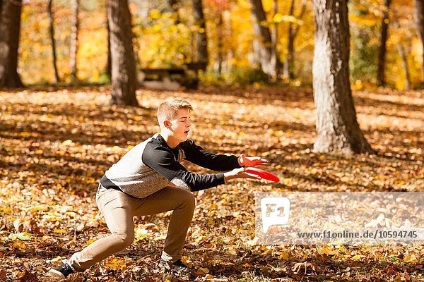 Teenager Junge fängt fliegende Scheibe im Herbstwald
