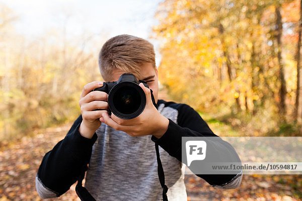 Portrait of teenage boy photographing in autumn forest