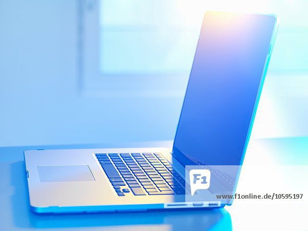Seitenansicht des offenen Laptops auf dem Schreibtisch Sonnenlicht kommt durch das Fenster