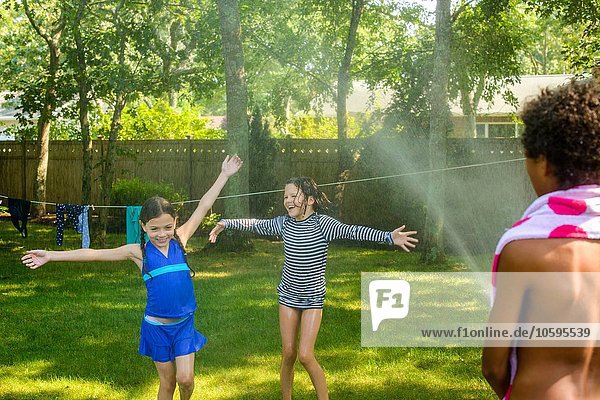 Drei Kinder spielen Garten mit Gartenschlauch