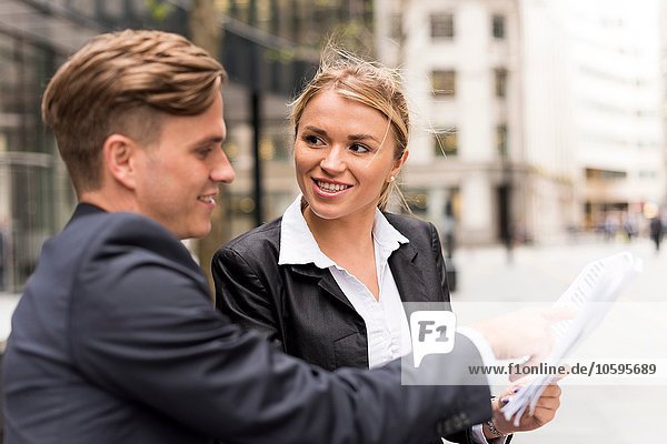 Businessman and businesswoman meeting outside office building  London  UK