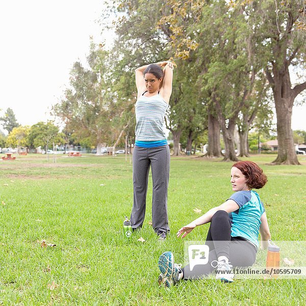Junge Frauen in Sportbekleidung auf Rasen Stretching
