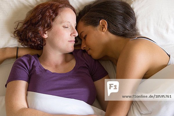 High angle view of lesbian couple lying in bed hugging  sleeping
