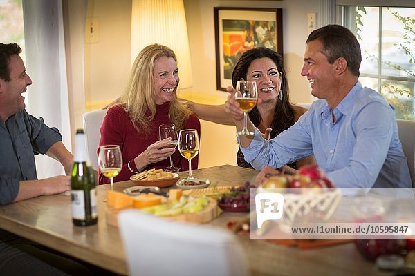 Zwei reife Paare trinken Wein und plaudern auf der Dinnerparty