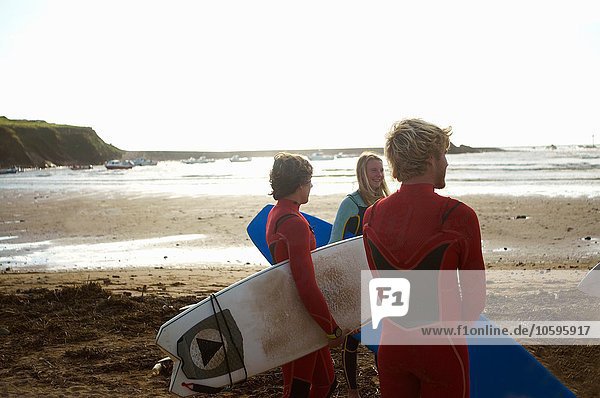 Surfergruppe am Strand stehend  Surfbretter haltend  Rückansicht