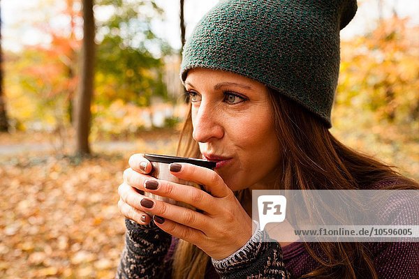 Junge Frau trinkt Kaffee im Herbstwald