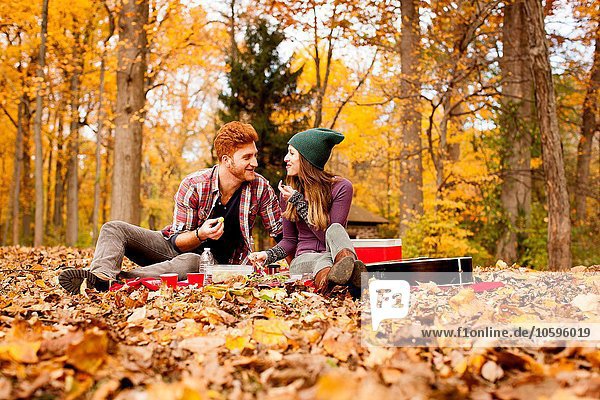 Happy young couple having picnic in autumn forest