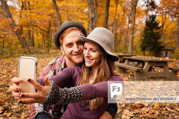 Young couple taking smartphone selfie in autumn forest