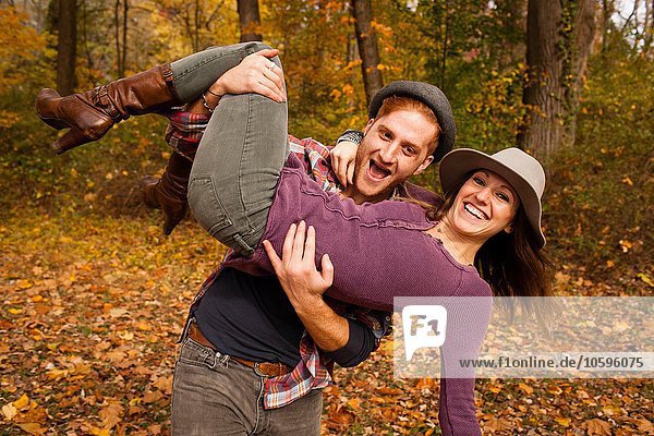 Portrait eines jungen Paares  das im Herbstwald herumalbert.