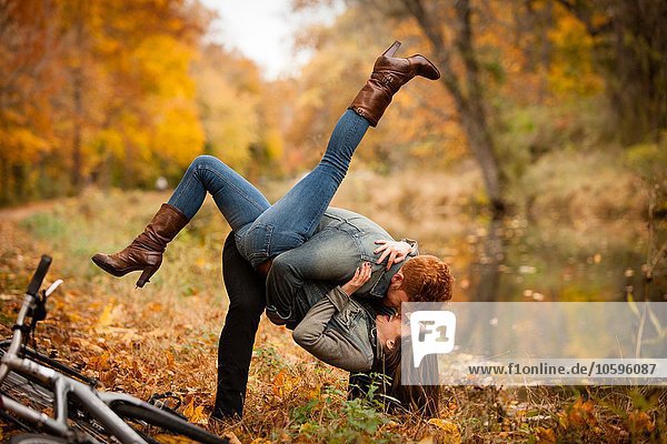 Romantic young couple fooling around on riverside in autumn