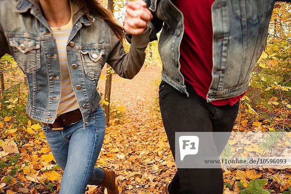 Cropped shot of romantic young couple running through autumn forest