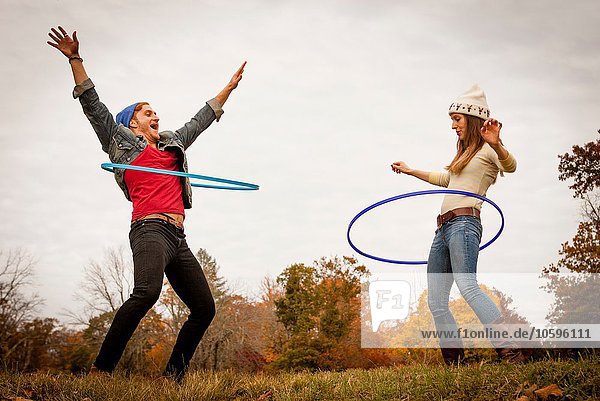 Young couple playing with plastic hoops in autumn park