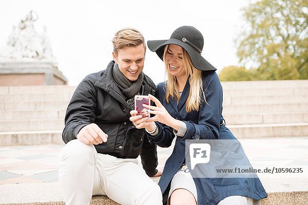 Junges Paar auf Schritt und Tritt beim Lesen von Smartphone-Texten  London  England  UK