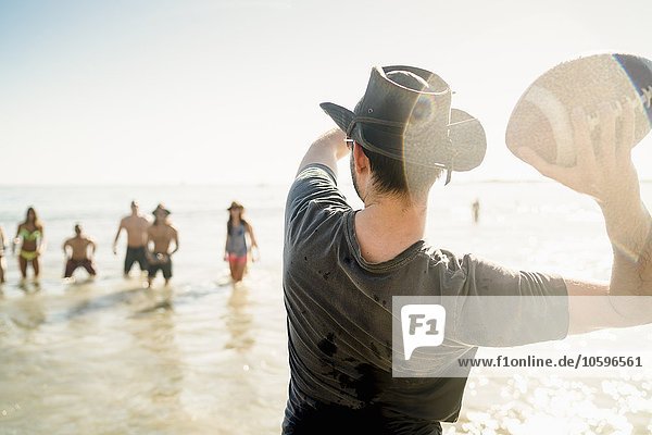 Junger Mann wirft American Football Ball an Freunde im Meer in Newport Beach  Kalifornien  USA