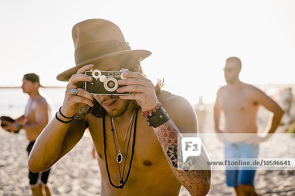 Portrait of young man taking photographs on Newport Beach  California  USA