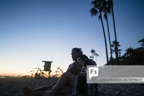 Romantic young couple sitting on beach watching sunset  Newport Beach  California  USA
