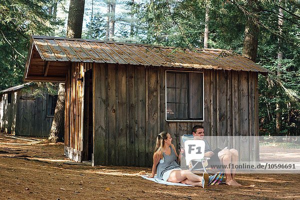 Junges Paar entspannt sich vor der Hütte im Wald
