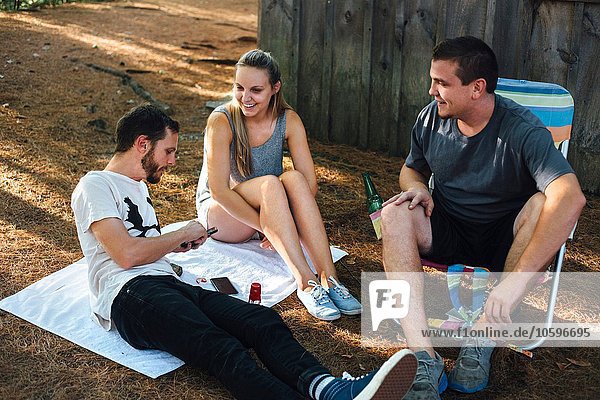 Drei erwachsene Freunde entspannen sich vor der Hütte im Wald