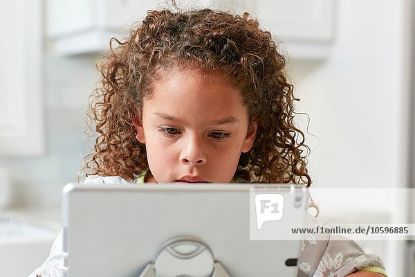 Girl using digital tablet looking down concentrating